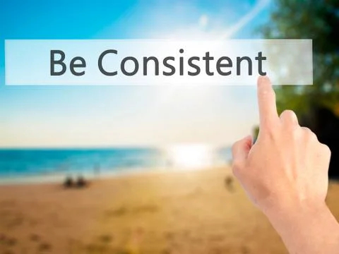 Be Consistent - Hand pressing a button on blurred background concept on visua Foto stock