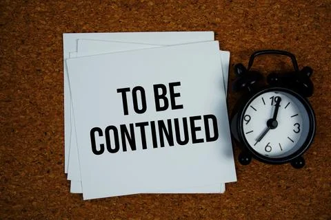 To Be Continued text on sticky note with alarm clock on cork paper background Stock Photos