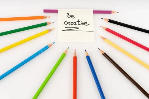 Be Creative Message Surrounded by Vibrant Color Pencils on White Background.. Stock-Fotos