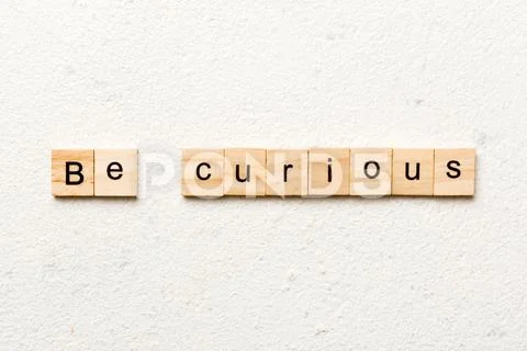 Be curious word written on wood block. be curious text on table ...