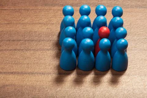 Be different, red among blue figurines Stock Photos