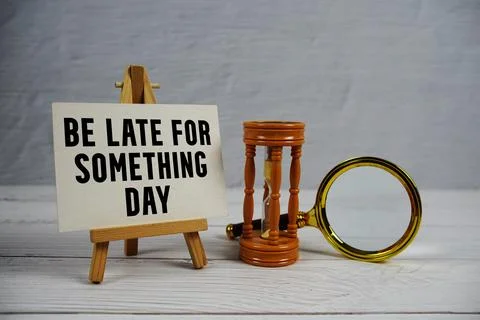 Be Late For Something Day text with hourglass and magnifying glass on woode.. Stock Photos