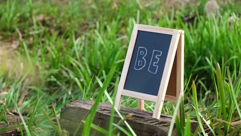 Be Message on Small Chalkboard in Meadow Grass Stock Footage 335999119