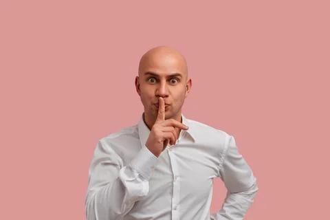 Be quiet please. Pleasant looking bald man with bristle, makes hush gesture,  Stock Photos