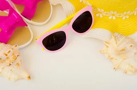 Beach accessories and sea shells. Female hat, slippers, glasses, sea shells Stock Photos