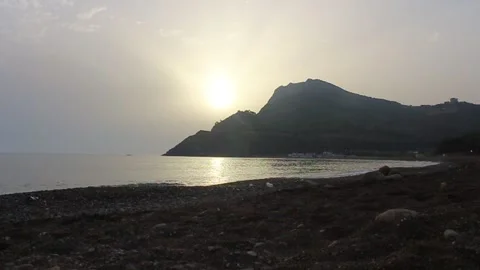 A beach and a mountain with clouds above them on a beautiful sunny day Stock Footage 136943905