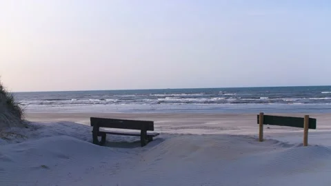 Beach and ocean of ameland with a bank and sign in foreground Stock Footage