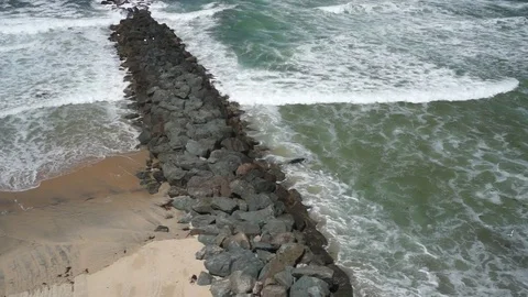 Beach and Ocean Sea Wall Flyby by Aerial Drone Stockbeeldmateriaal 70534357