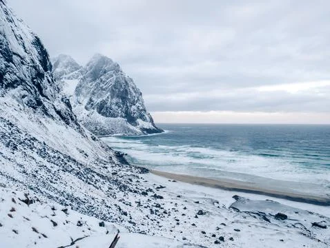 Beach and ocean surrounded by mountains during winter in Kvalvika Beach Foto stock