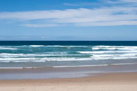 Beach and Ocean Waves Under Cloudy Blue Sky Foto stock
