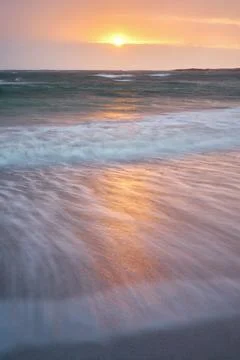 Beach and waves reflecting the sunlight in the foreground Stock Photos