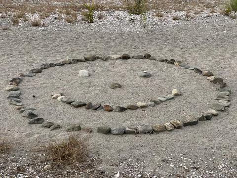 Beach artwork; a smiley face made out of rocks on a beach Stock Photos