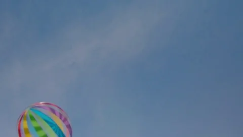 Beach ball flying through blue sky - handheld - slow motion 01/02 Stock Footage 80757277