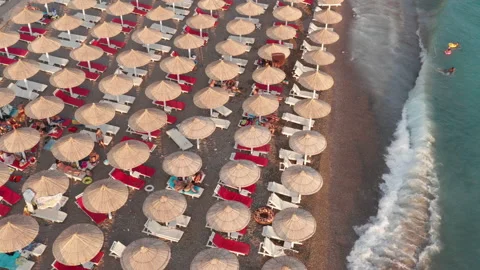 Beach beds and rows of thatch umbrellas - tiki straw parasols by the sea Stock Footage 212948233