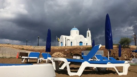 Beach beds and the Saint Nicholas Chapel in Protaras on a rainy day Stock Footage 90647666
