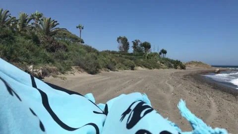 A beach blanket blowing in the strong wind on a sandy beach in Spain Stock Footage 132510732