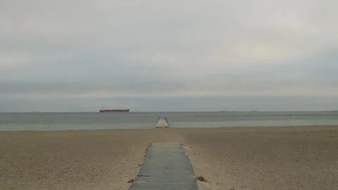 Beach Boardwalk Leading to Ocean with Distant Cargo Ship Stock Footage 328162890