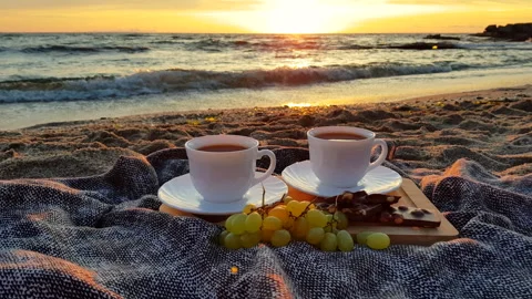 Beach breakfast with coffee, chocolate and grapes at sunrise. Stock Footage 337180356