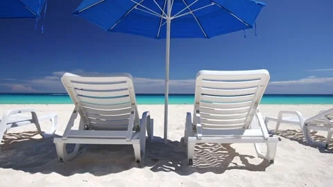 Beach calm scene with empty white sunbeds and blue sun umbrella near Caribbean Stock Footage 153103412
