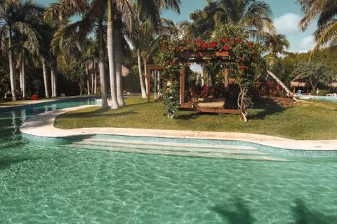 Beach canopy by the pool surrounded by palm trees Stock Photos