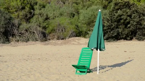 Beach chair and umbrella blows in the wind Stock Footage