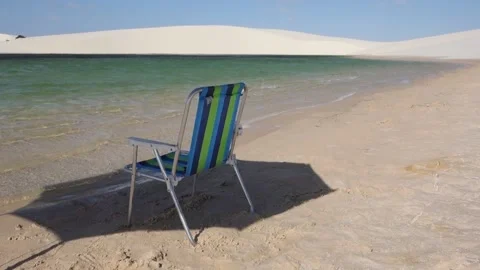 Beach chair under umbrella shadow facing an amazing turquoise lagoon Vidéo 160246153