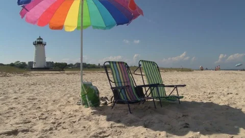 Beach chairs and umbrella in front of lighthouse Stock Footage 74062255