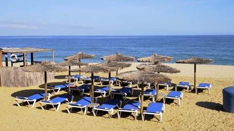 Beach chairs on the white sand beach with blue sky and sun Stock Footage 107775267