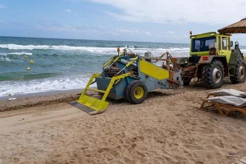 Beach cleaning machine pulled by tractor on sandy coast Fotos Stock