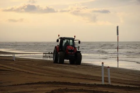 Beach Cleaning Tractor Working on Sandy Shore at Sunset Stock Photos