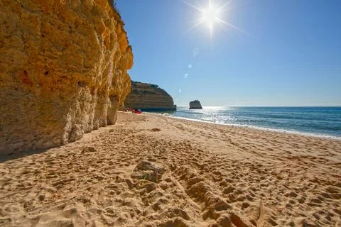 Beach with cliffs and sun reflection Algarve Fotos Stock