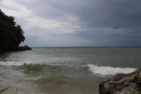 Beach, cloudy sky, waves, sea, rocks and trees 스톡 사진