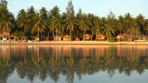 Beach with coconut palm trees and bungalows which is reflected in sea water Stock Footage 118638563
