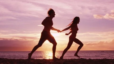 Beach couple running having fun holding hands on beach enjoying romantic sunset Stock-Footage 79899246