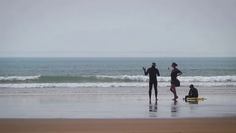 Beach - couple stood talking facing the sea. 库存影片 76981608