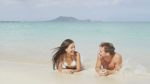 Beach couple on vacation relaxing in sand laughing having fun Stock Footage 46944853