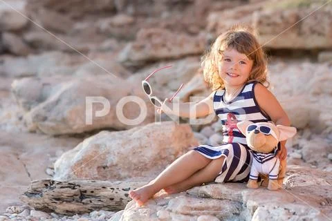 Beach cute girl posing on a rocky beach barefooted with curly hair wearing sa Stock Photos