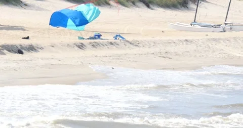 Beach day with blue canopy and boats along the shore in summer Video stock 281815752