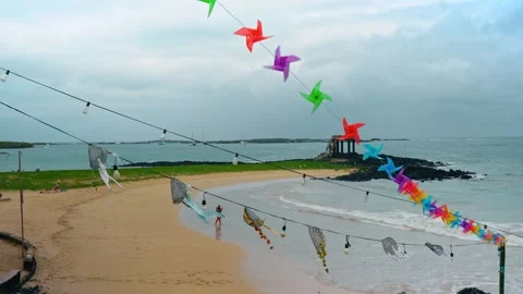 Beach decorated with light bulb and windmills garlands. Man takes video of the Stock Footage 334705175