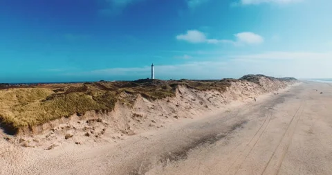 Beach dunes lighthouse crane up blue sky aerial Stock Footage 153514844