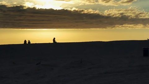 Beach during sunset with birds flying and people enjoying view Stock Footage 87842963