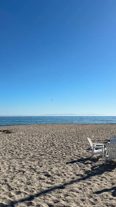 Beach with empty lounge chairs by ocean on sunny day Stock Footage 320312722