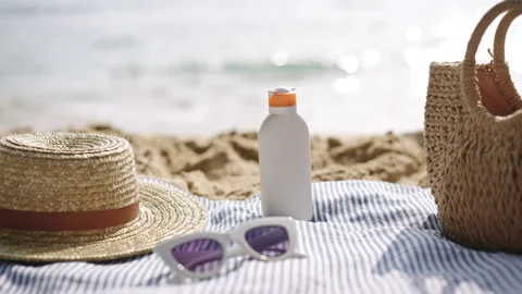 Beach essentials arranged on blue striped towel. Sunscreen bottle, UV protection Stock Footage 270065651