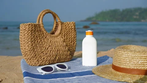 Beach essentials arranged on sandy shore for summer day. Sunscreen bottle with Stock Footage 266818693