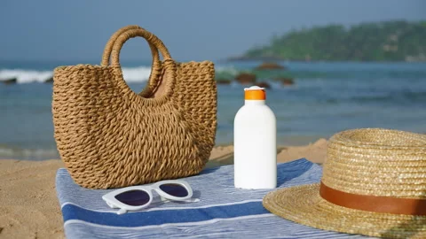 Beach essentials arranged on sandy shore bottle of sunscreen, stylish straw hat Stock Footage 270075137