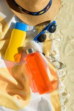 Beach Essentials with Hat, Sunglasses, Sunscreen, Kid Mold and Water Bottle.. Stock Photos