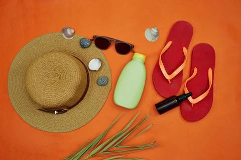 Beach Essentials on Orange Background Featuring Hat and Sandals Stock Photos