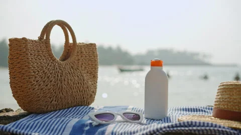 Beach essentials on sunny seaside day, bottle with sunblock SPF alongside trendy Stock Footage 270424092