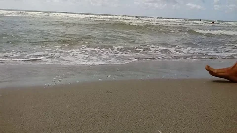 Beach with feet passing in the foreground with waves in the background Stock Footage 116405942