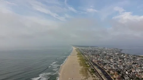 A beach with a few people walking on it and a city in the background Stock Footage 313442013